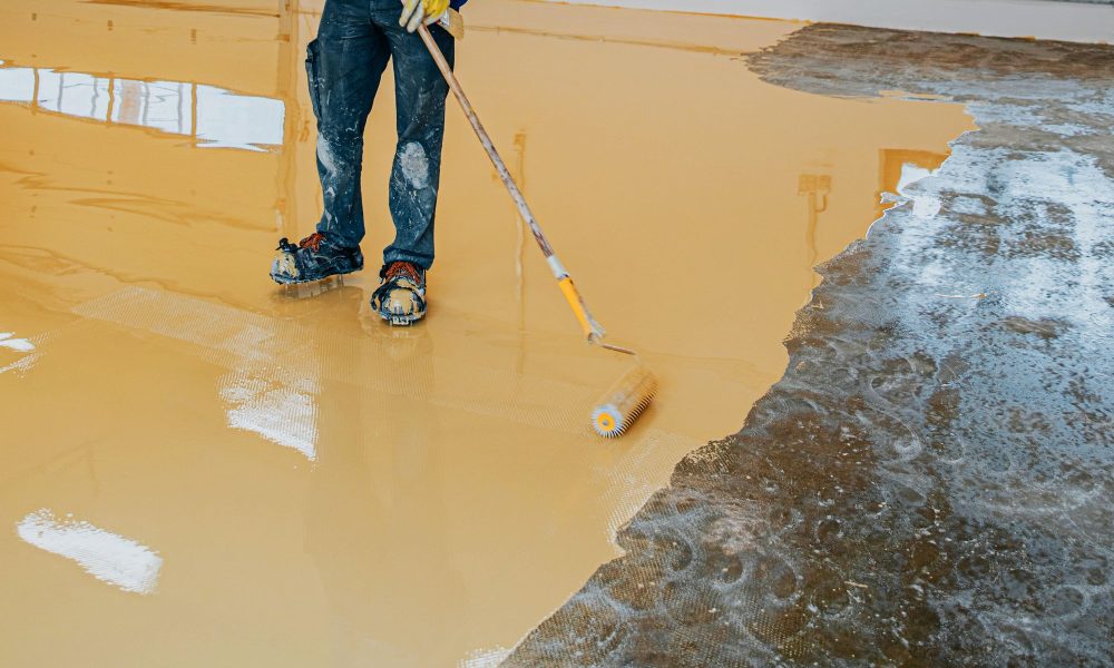 worker-coating-floor-with-selfleveling-epoxy-resin-industrial-workshop